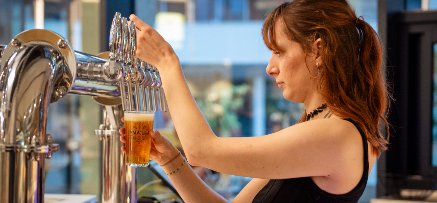 Le CraftBar côté tireuse à bière, la serveuse tire une bière dans une pinte.